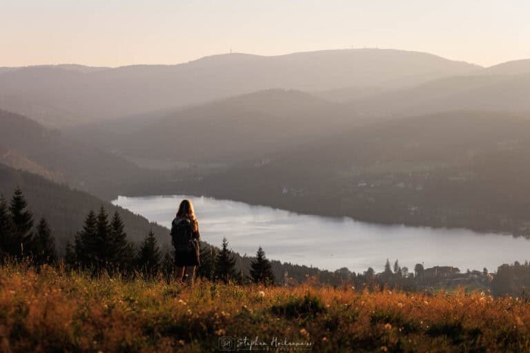 Person steht in Abendlichtstimmung am Hochfirst mit Blick Richtung Titisee im Schwarzwald