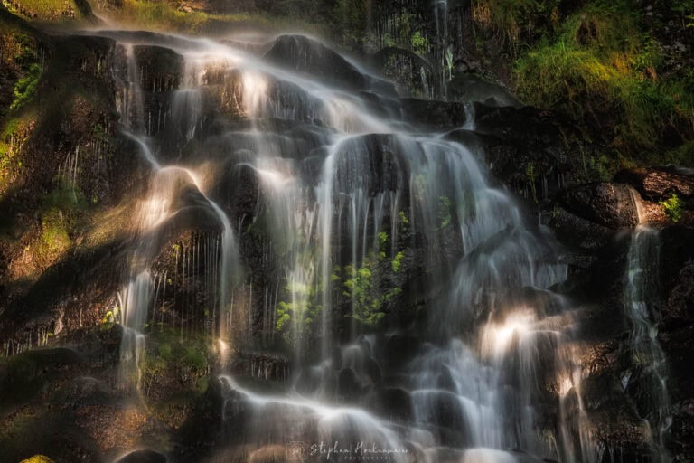 Detailausschnitt des unteren Wasserfalls der Zweribach-Wasserfälle im Schwarzwald mit moosigen Felsen und weichem Wasserfluss.