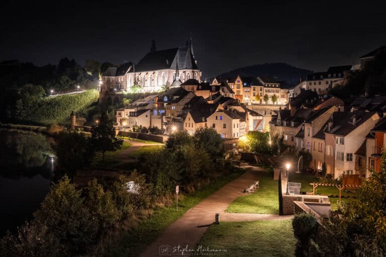 Kirche St. Laurentius in Saarburg bei Nacht mit beleuchteter Altstadt
