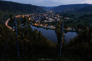 Moselschleife bei Kröv zur späten blauen Stunde mit Blick durch die Weinberge auf Mosel, Ort und Lichtspuren