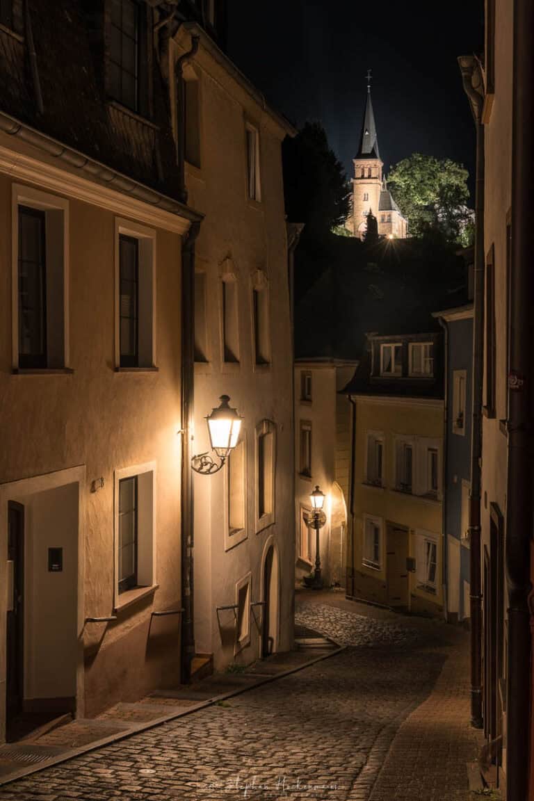 Nächtliche Gasse in der Altstadt von Saarburg mit beleuchteter Kirche im Hintergrund
